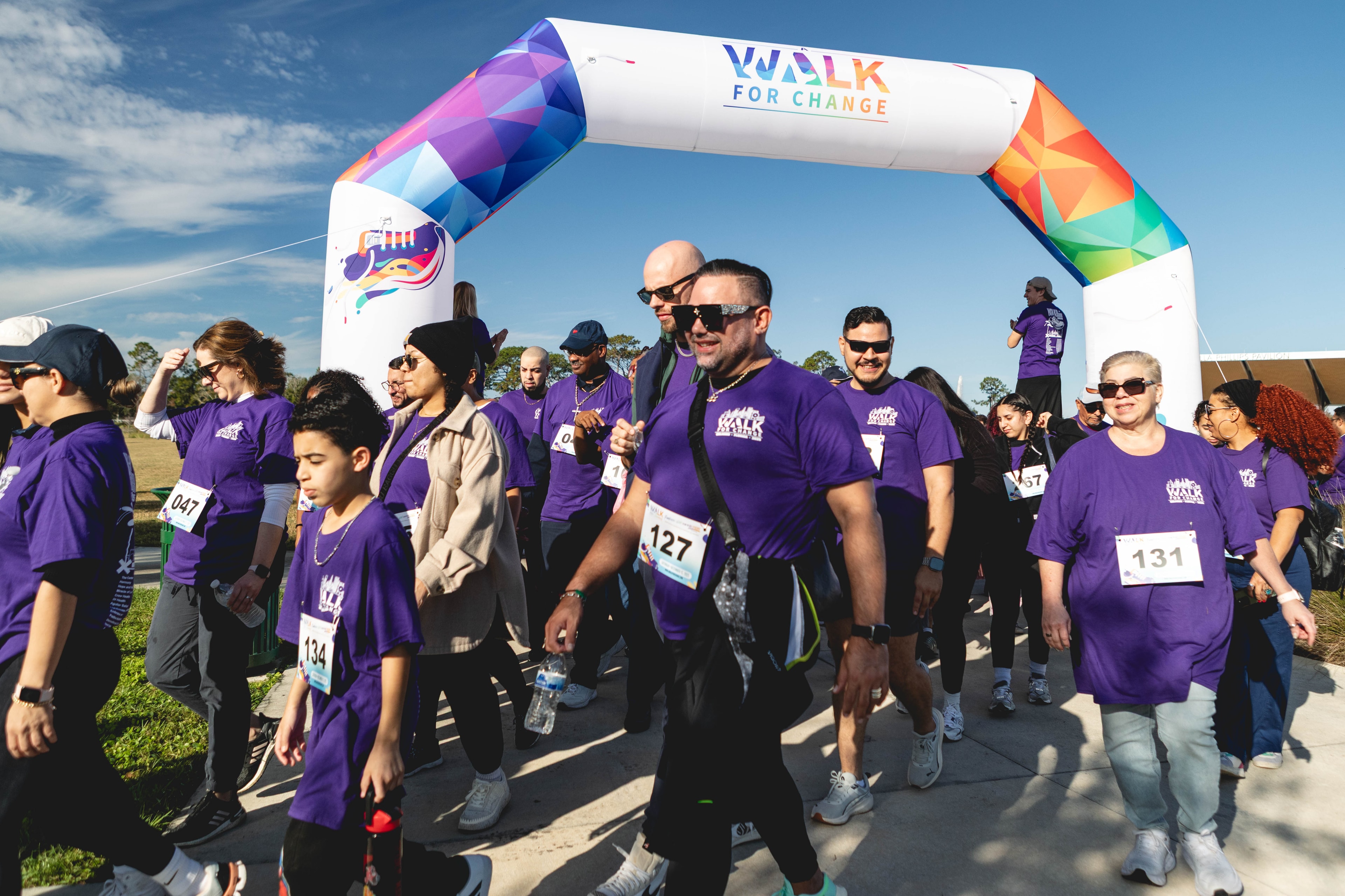 Participants walking under the Walk for Change arch at the community event